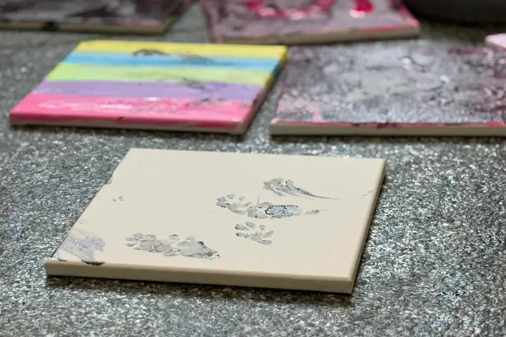 Canvas paintings on a textured floor, one with rainbow stripes, others with abstract designs.